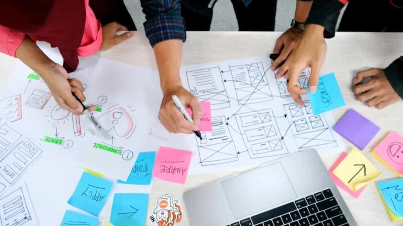 A group of employees work together on developing wireframes at a table.