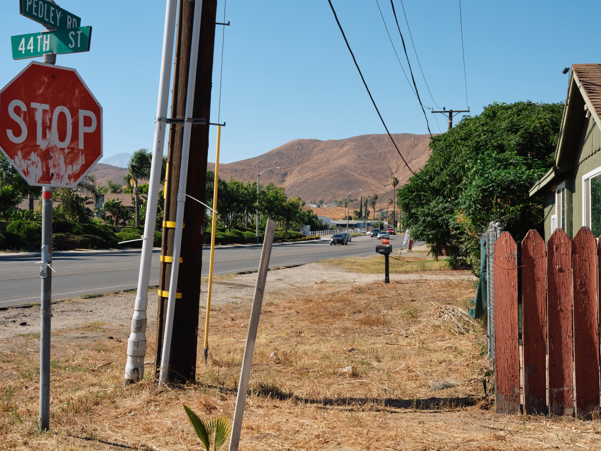 A photo of a street in Riverside, California. There is a stop sign in the lefthand foreground and brown hills in the background.
