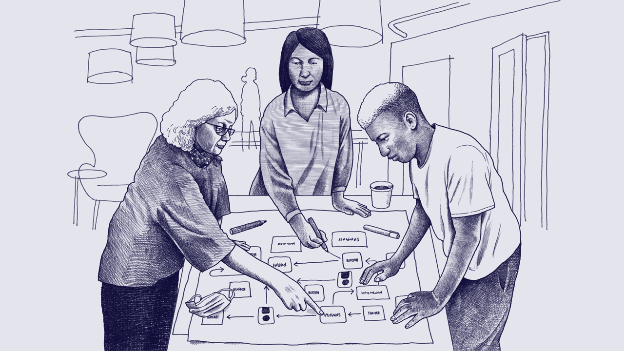An older white woman, a middle-aged Native American woman, and a young Black man stand together at a table and point to a flow chart.